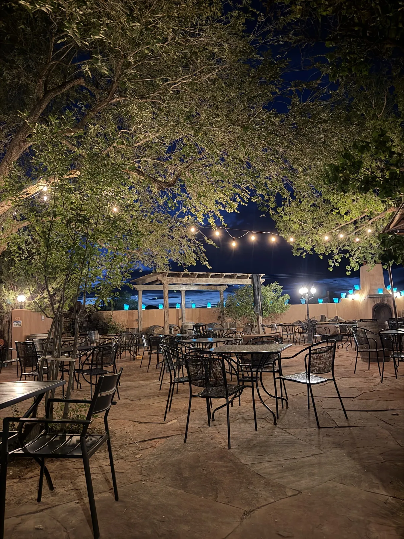 Beer Creek Brewing Company's outdoor patio at night, with string lights, trees and tables on the Turquoise Trail near Santa Fe.